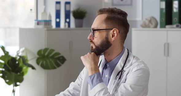 Portrait of Pensive Caucasian Male Doctor Looking at Camera in Clinic Office