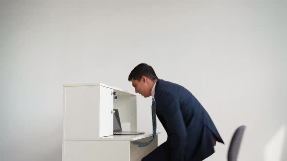 Business Man in Formal Clothes Jumps Over Desk and Sits Down to Work at Laptop