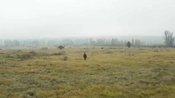 Documentarist with a camera walking in a foggy moorland,autumn,Czechia.