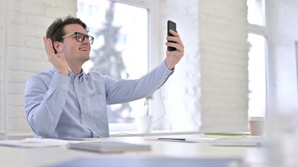 Cheerful Working Young Man Doing Video Chat on Smartphone