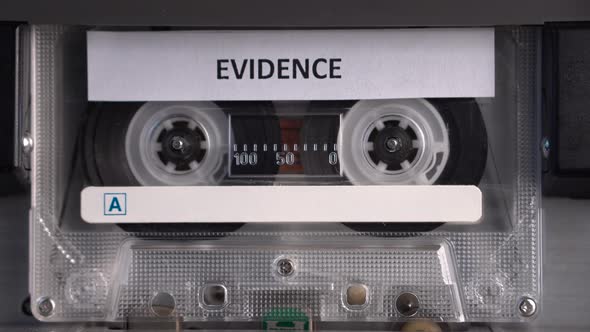 Cassette Tape With Evidence Audio Recording Rolling in Vintage Deck Player