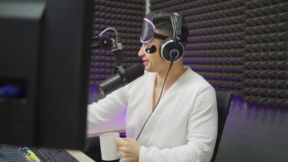 Radio Dj in Sleep Mask and Cosmetic Patches Drinking Coffee on Broadcast