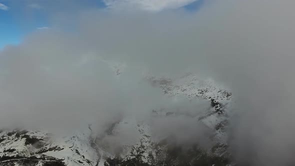 Flying Through Clouds Between Snow Mountains