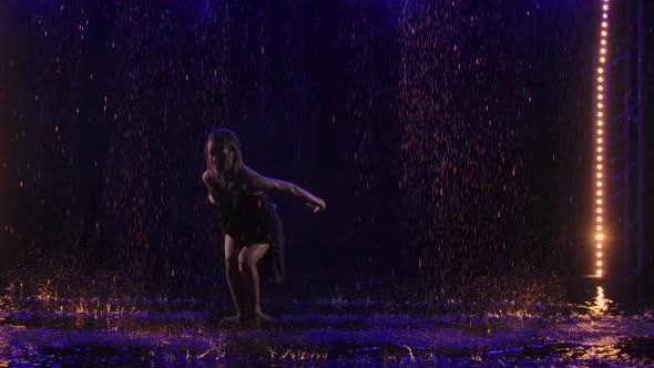 A Slender Blonde is Dancing Bachata Among the Raindrops and Splashing Water