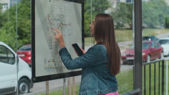 Woman Looking on the Scheme of Public Transport While Standing at the Tram Station Outdoors.