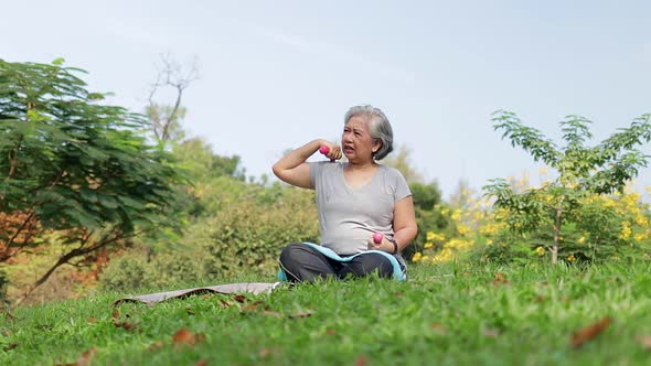 Asian elderly woman Sit and exercise in the park in the morning.