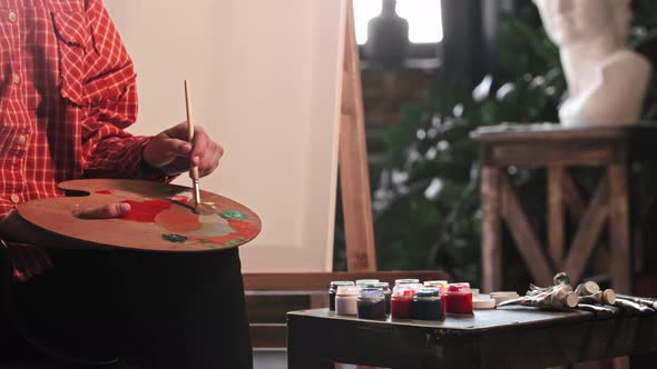 A Young Woman Artist Mixing Warm Colors on the Palette