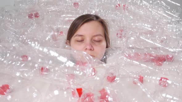 Dehydrated Sick Woman Is Lying in a Pile of Plastic Bottles. Environmental Pollution Problem. Stop