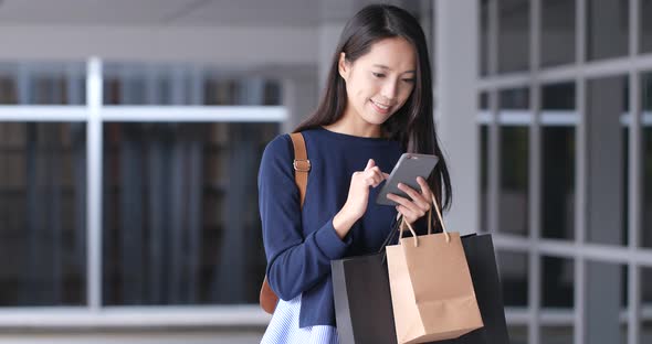 Woman use of mobile phone and holding shopping bag