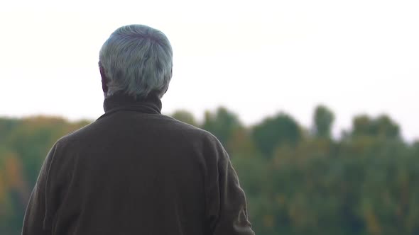 Retired Man Looking Into Distance at Bright Autumn Trees Thinking About Life