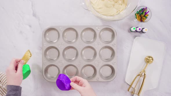Flat lay. Step by step. Scooping cupcake batter into a foil cupcake liners to bake vanilla Mardi Gra