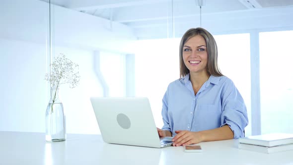 Smiling Young Woman at Work looking Toward Camera