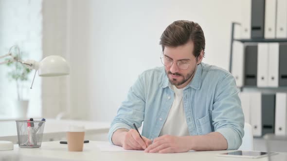 Pensive Young Man Writing on Paper Thinking