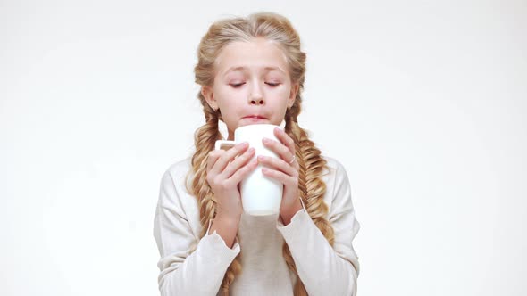 Small Caucasian Beautiful Caucasian Girl with Luxurious Long Blonde Hair Drinking Hot Milk From Cup