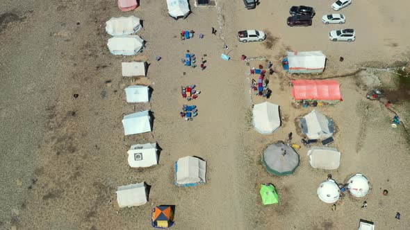 Aerial drone top down view of cars, tents and yurts at a dirt campground in the high-altitude alpine