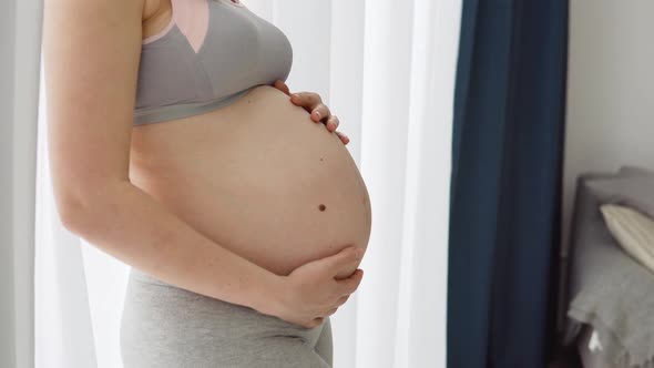 A Pregnant Woman Holds Her Hands on Her Belly