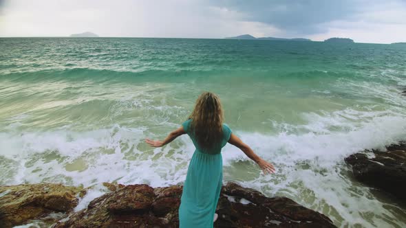 Woman Meditates Relaxes on a Rock Reef Hill in Stormy Morning Rain Cloudy Sea