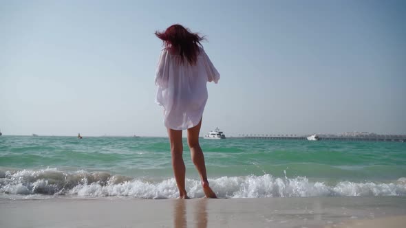 Woman in a White Shirt Walks Along the Beach of the Persian Gulf in Dubai