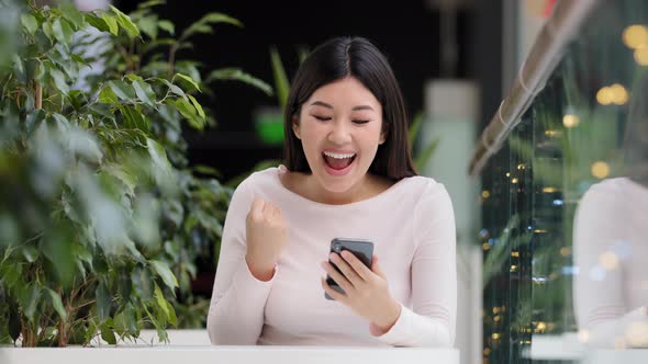 Asian Korean Girl User Freelancer Player Woman Sitting in Coffee Shop at Table in Office with Phone