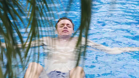 Close Up View of a Young Caucasian Man Lying and Floating in Water in the Pool
