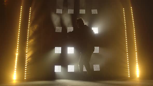 Silhouette of Teenager in Casual Clothers Dance Improvising in Black Studio. Dark Studio with Smoke