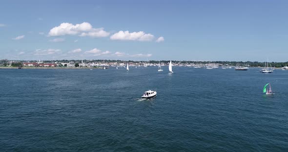 A small sail boat races past a yacht in the waters of Newport Rhode Island.