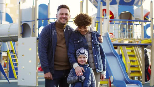 Smiling Caucasian Family of Three Posing at Playground