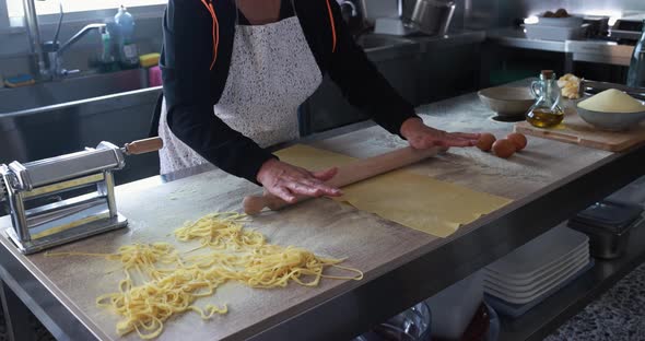 Woman preparing dough for tagliatelle inside pasta factory