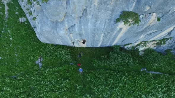 Aerial drone view of a man rock climbing up a mountain.