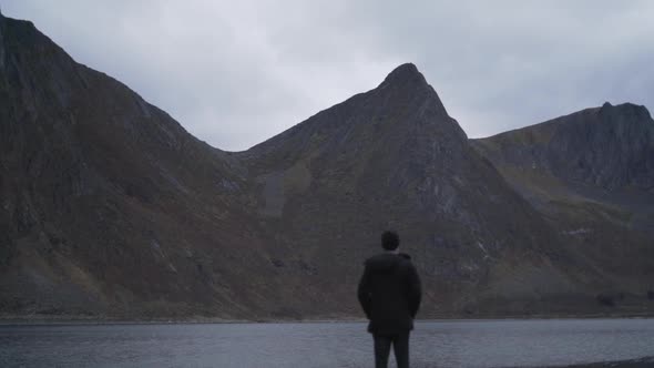 Man Standing On Rocks Looking Over Fjord