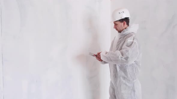 A Man in a Protective Suit and Helmet Holds a Spatula in His Hand