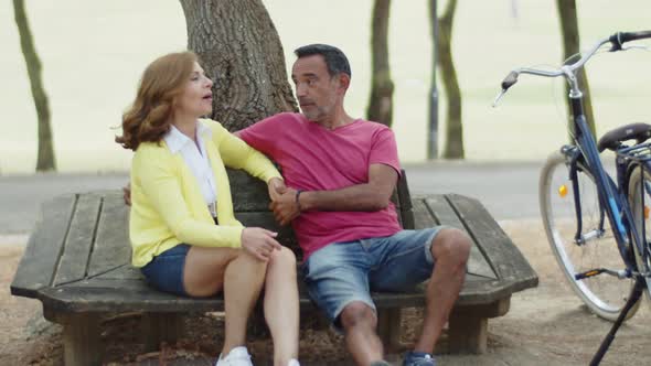 Senior Couple Sitting Together on Bench in Summer Park