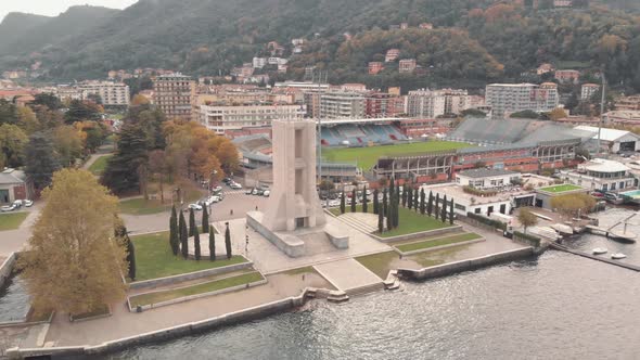 Tower-like stone war monument with Stadium Giuseppe Sinigaglia on background, Como, Lombardy, Italy.