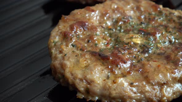 The fried cutlet for hamburger rotates on the grill pan.