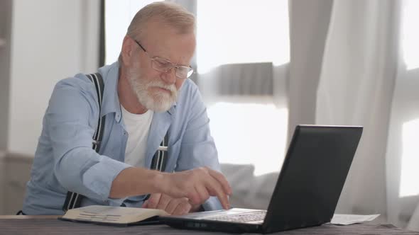 Attractive Old Pensioner with Glasses for Vision Works at Computer with Bank Accounts and Payments