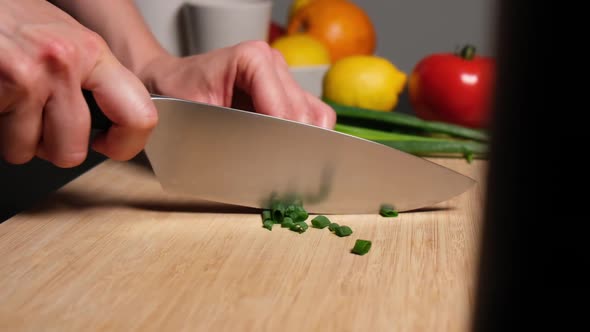Chopping spring onion on wooden board slow motion.