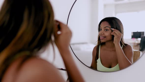 Young Hispanic Latina Woman Applying Makeup in Bedroom