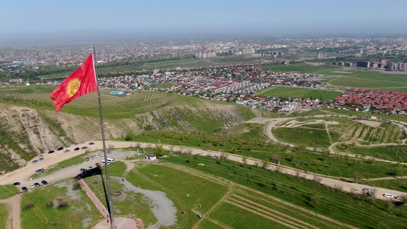 Aerial view of Bishkek city from the mountains. Flagpole with Kyrgyzstan flag