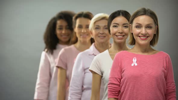 Smiling Women in Pink Shirts With Breast Cancer Ribbons Standing in Row, Support