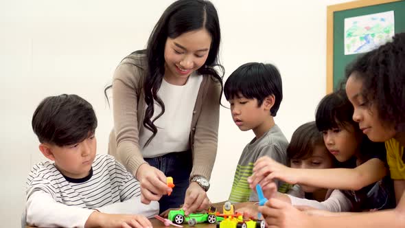 Asian School Teacher Assisting Elementary Students in Science Classroom