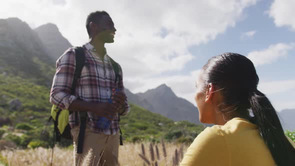 African american couple talking to each other while trekking in the mountains