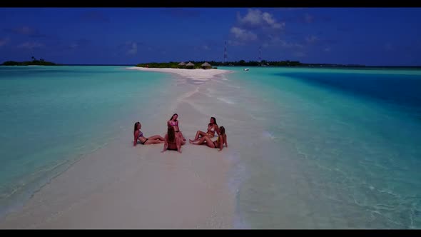 Beautiful ladies relaxing on paradise lagoon beach lifestyle by blue green sea and white sandy backg