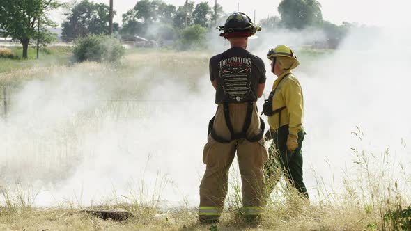 Firemen standing watching controlled fire