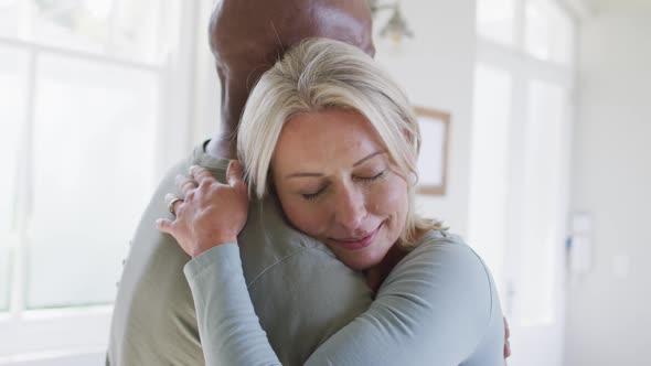 Mixed race senior couple hugging each other at home