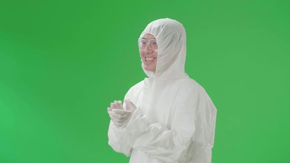 Side View Of Man Wearing Protective Uniform Ppe And Clapping His Hands In The Green Screen Studio