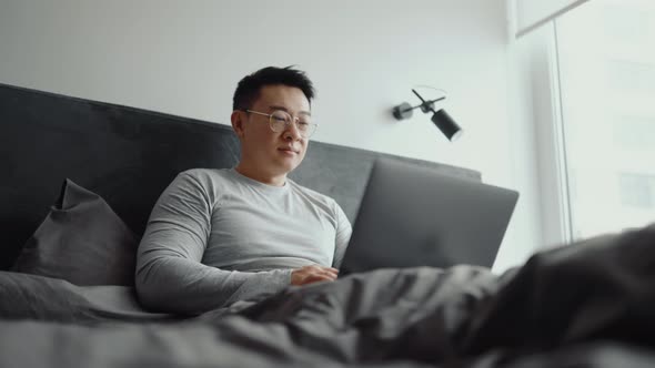 Man working on laptop on the bed