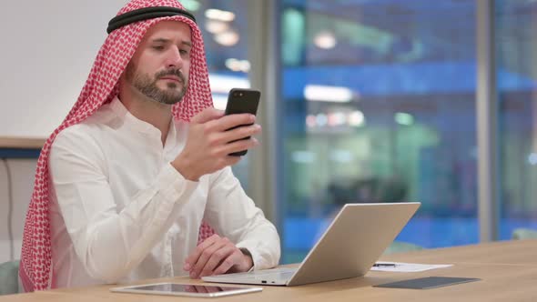 Expert Arab Businessman with Laptop Using Smartphone