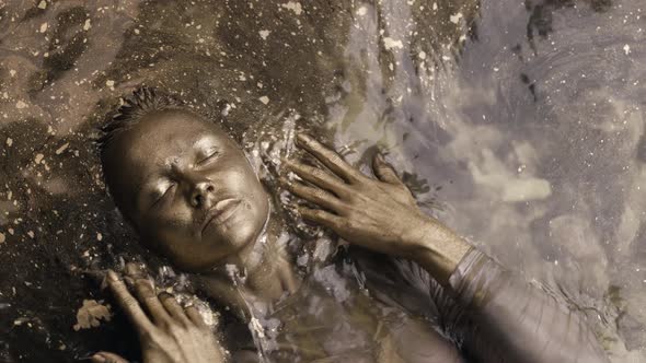 Art and Fashion Shot of Young Woman with Skin and Hair Covered By Golden Shiny Dye in Shallow