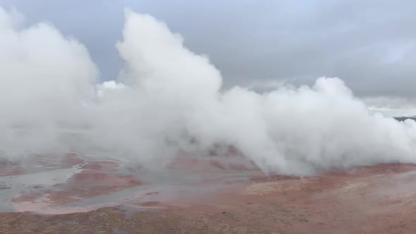 Aerial shot looking through the steam of a geothermal hot spring.