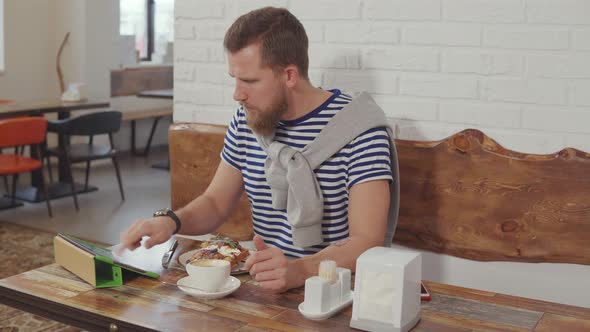 Man Eating Dessert and Surfing Web in Cafe.